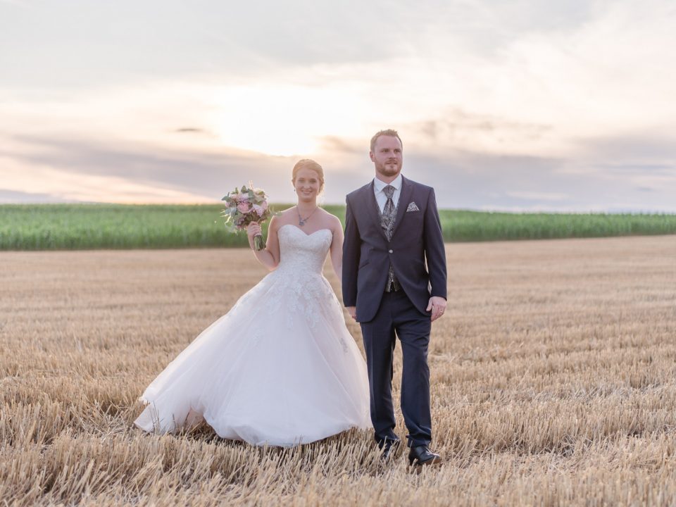 eine Braut und ein Bräutigam, die auf einem Feld stehen.