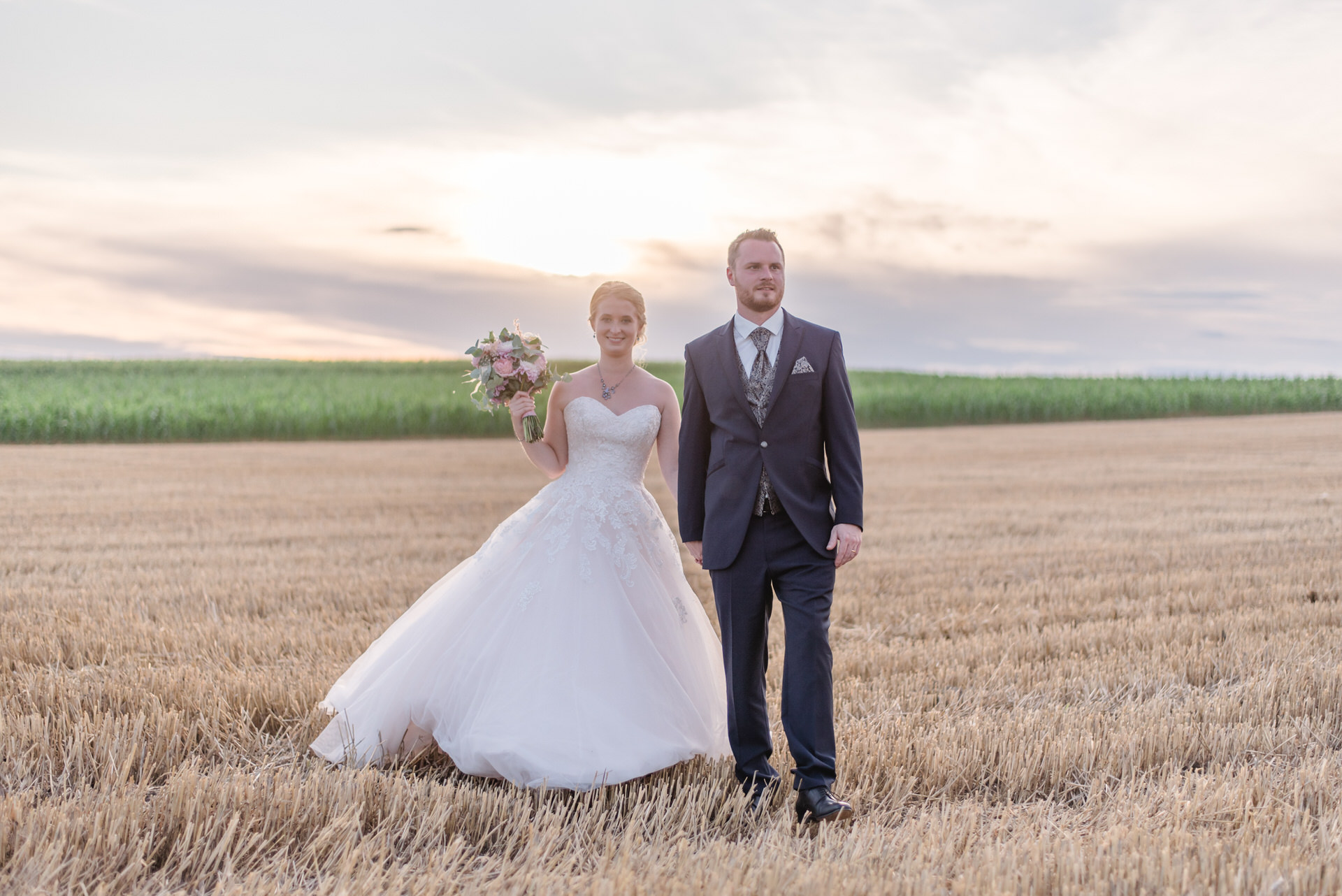 eine Braut und ein Bräutigam, die auf einem Feld stehen.