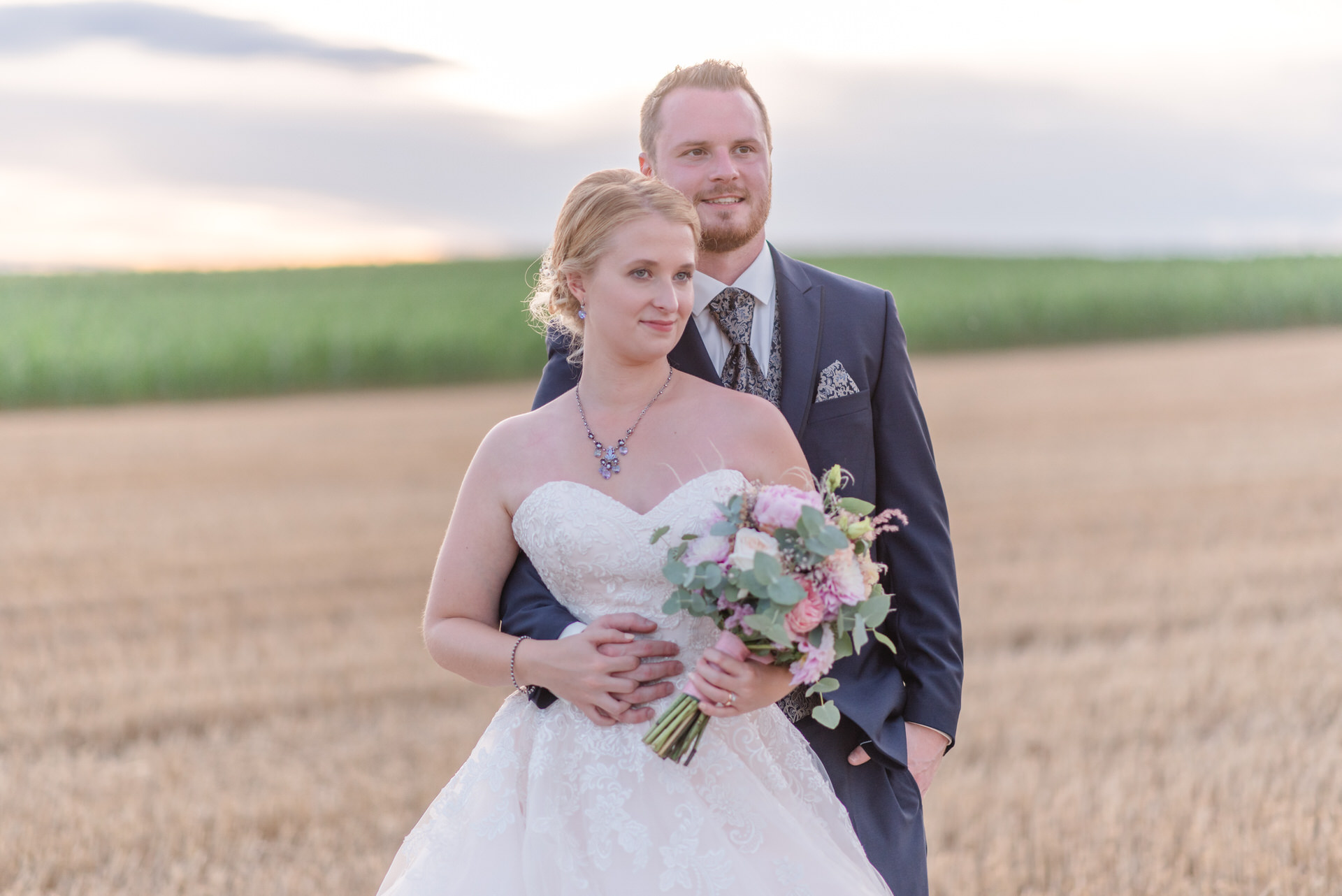 eine Braut und ein Bräutigam, die in einem Weizenfeld stehen.