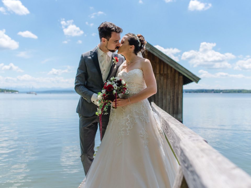 Eine Braut und ein Bräutigam, die auf einem Dock am Wasser stehen.