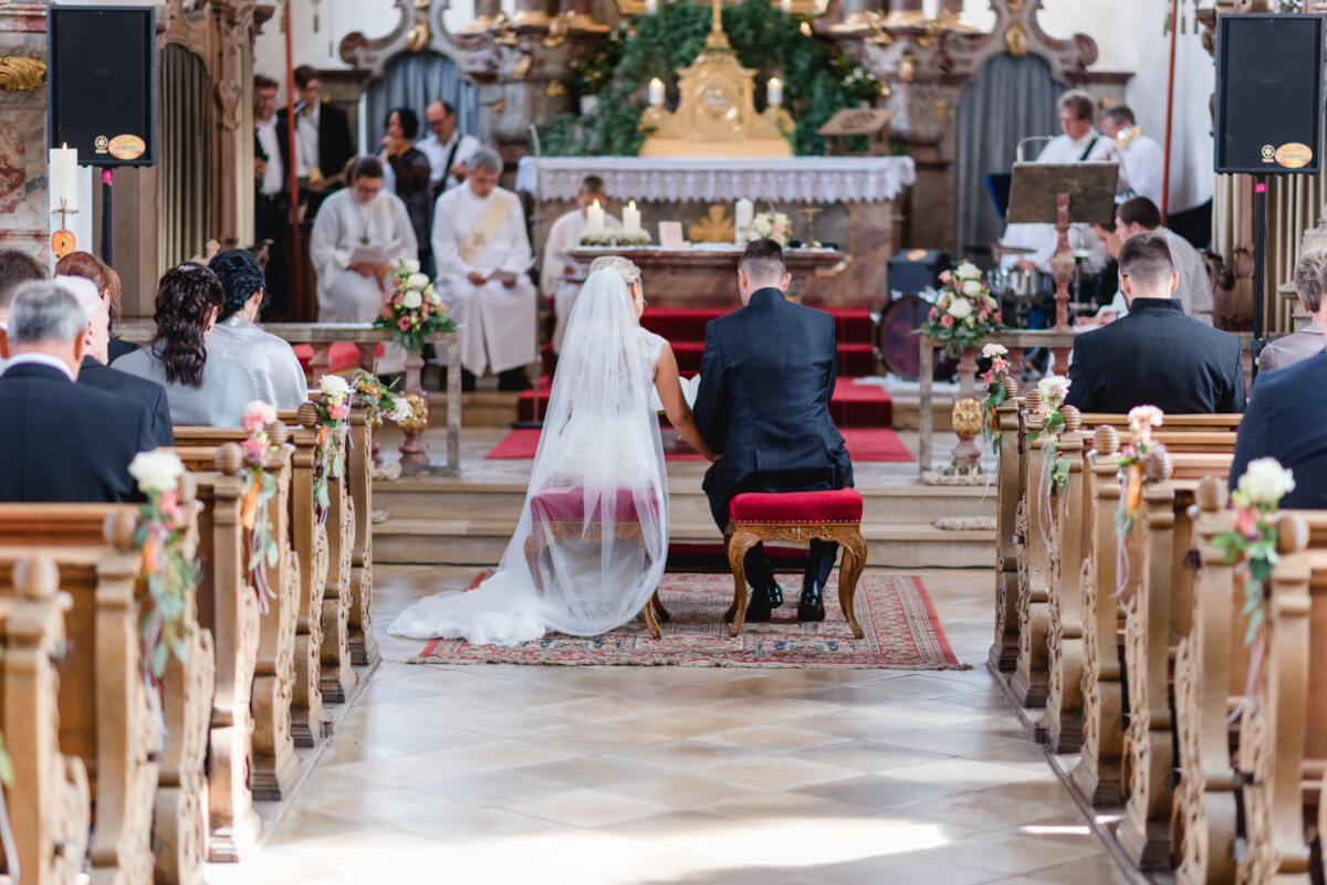 Janina_Daniel_Ettringen_00011 Ein Brautpaar sitzt am Altar.