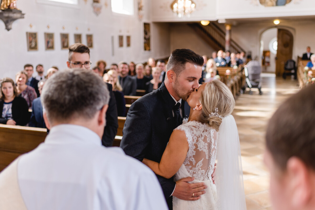 Janina_Daniel_Ettringen_00014 ein Brautpaar, das sich in einer Kirche küsst.