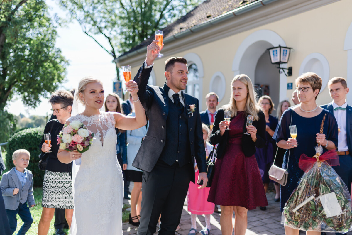 Janina_Daniel_Ettringen_00029 Ein Mann und eine Frau halten Weingläser hoch.
