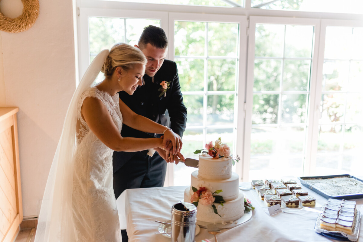 Janina_Daniel_Ettringen_00030 Braut und Bräutigam schneiden ihre Hochzeitstorte an.
