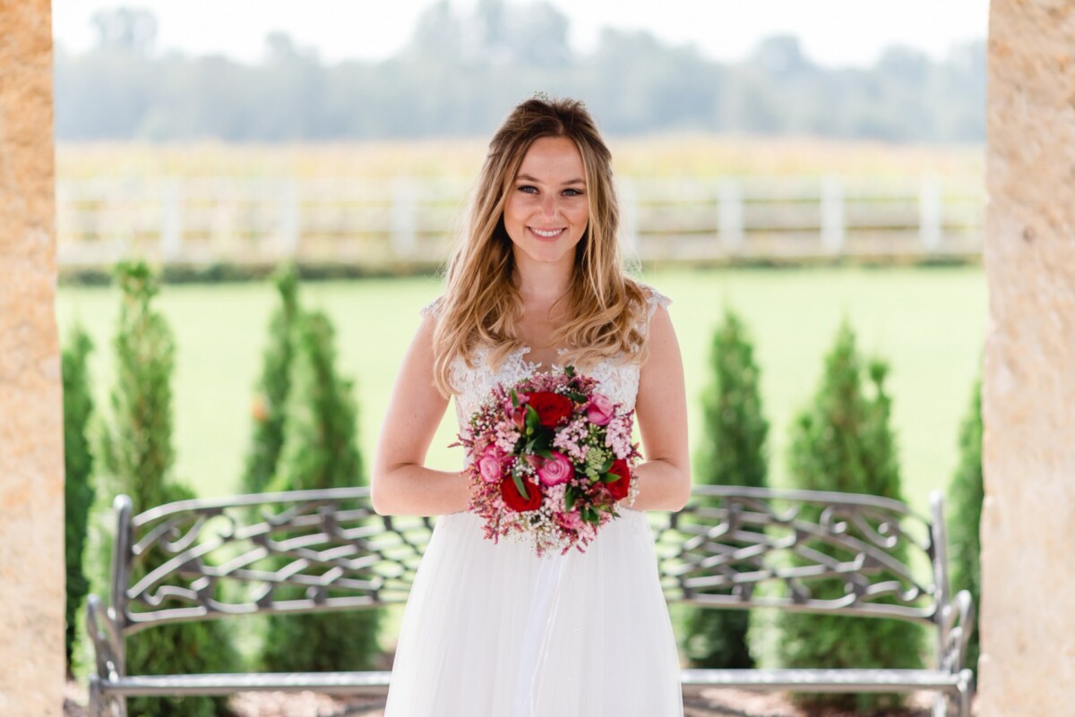 Julia_Marco_Donauwoerth_00011 eine Frau in einem Hochzeitskleid, die einen Blumenstrauß hält.