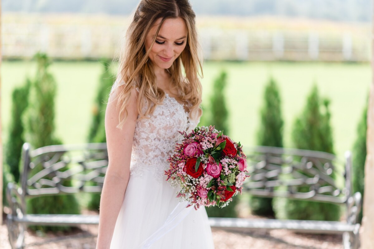 Julia_Marco_Donauwoerth_00013 eine Frau in einem Hochzeitskleid, die einen Blumenstrauß hält.