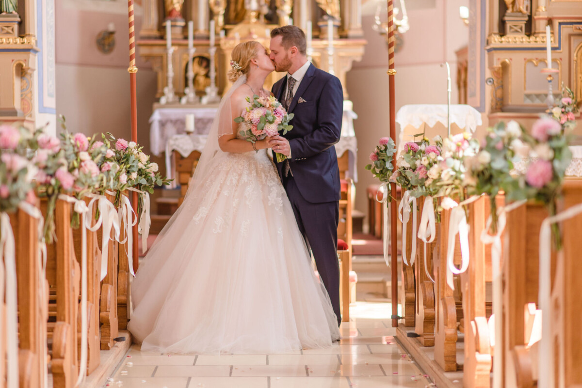 Natalie_Willi_Sulzemoos_00022 Ein Brautpaar küsst sich in einer Kirche.