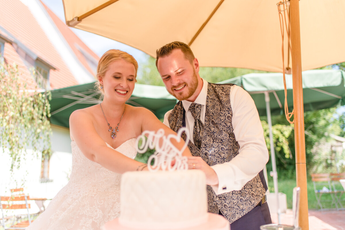 Natalie_Willi_Sulzemoos_00026 Ein Mann und eine Frau schneiden eine Hochzeitstorte an.