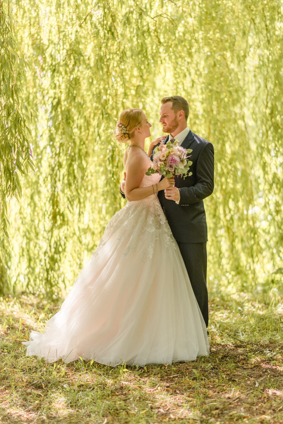 Natalie_Willi_Sulzemoos_00028 ein Brautpaar, das unter einer Weide steht.