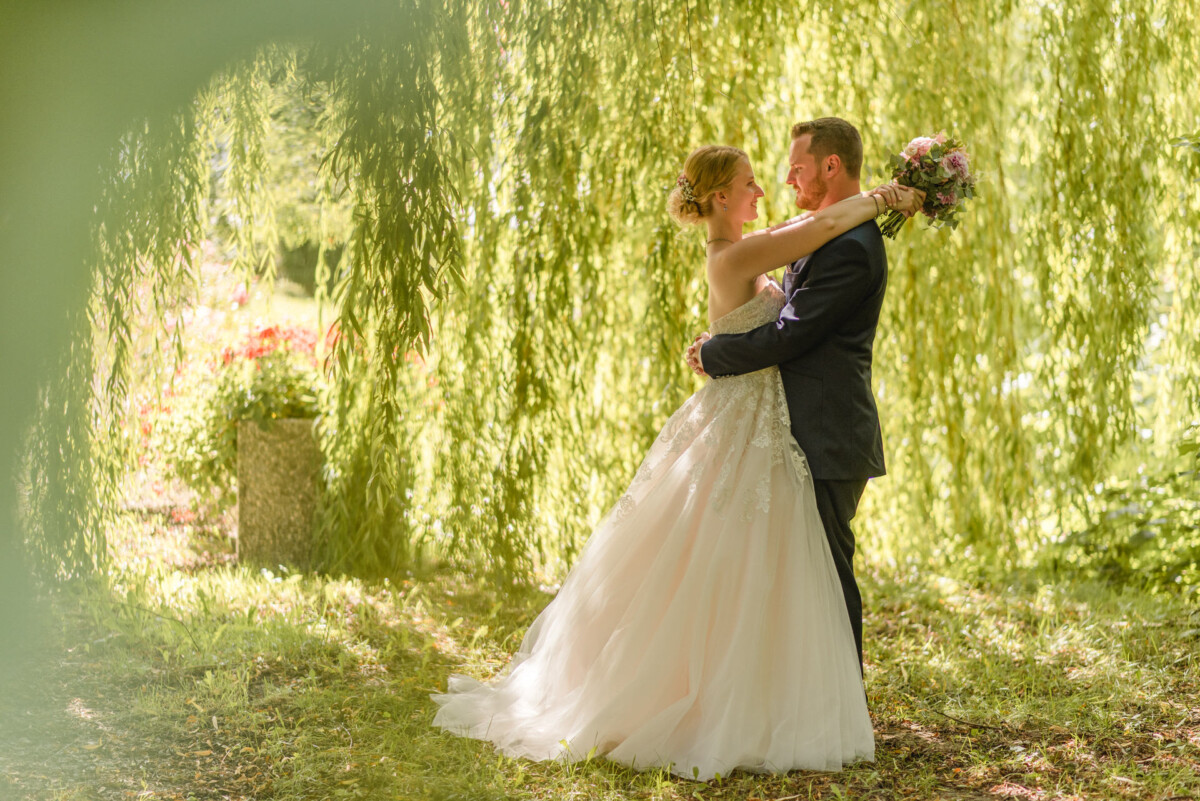 Natalie_Willi_Sulzemoos_00029 ein Brautpaar, das unter einer Weide steht.