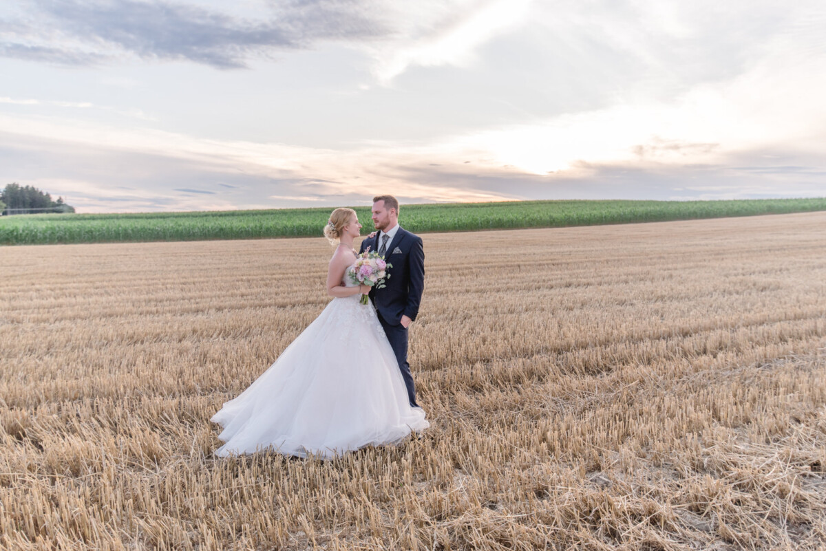Natalie_Willi_Sulzemoos_00039 eine Braut und ein Bräutigam, die auf einem Feld stehen.