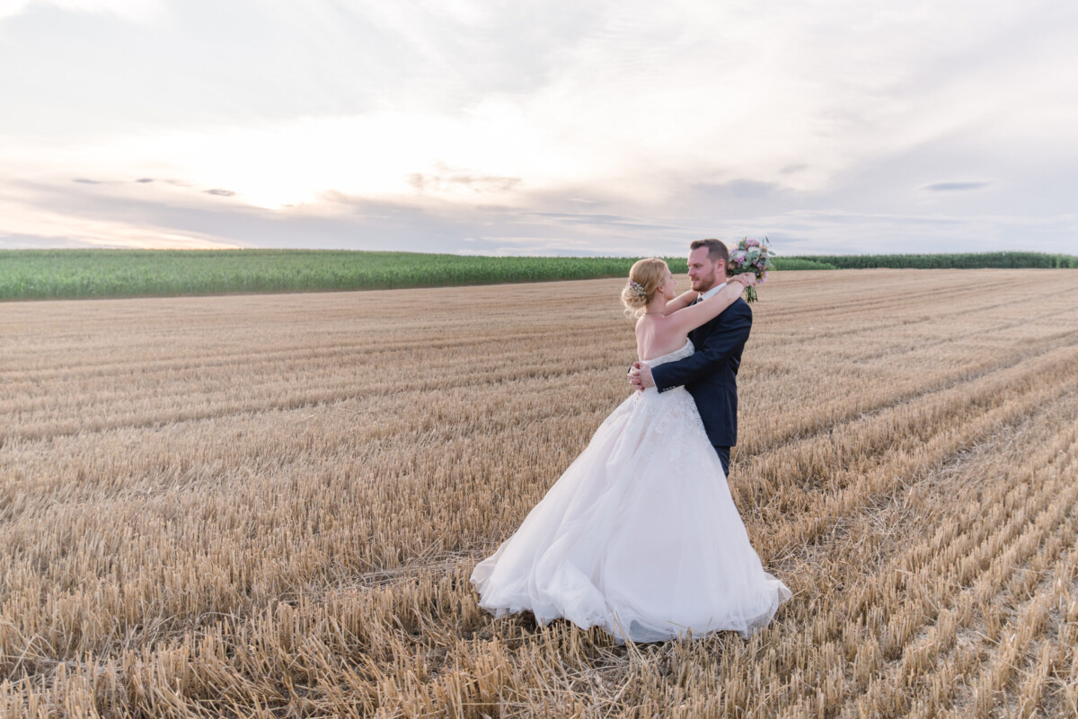 Natalie_Willi_Sulzemoos_00041 eine Braut und ein Bräutigam, die auf einem Feld stehen.