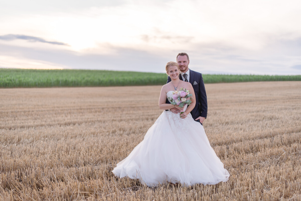 Natalie_Willi_Sulzemoos_00042 eine Braut und ein Bräutigam, die auf einem Feld stehen.