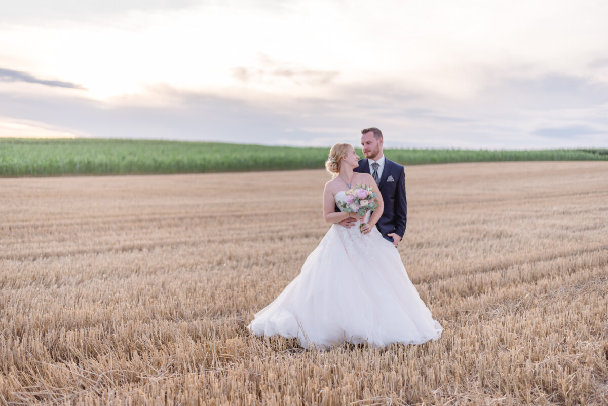 Natalie_Willi_Sulzemoos_00043 eine Braut und ein Bräutigam, die auf einem Feld stehen.