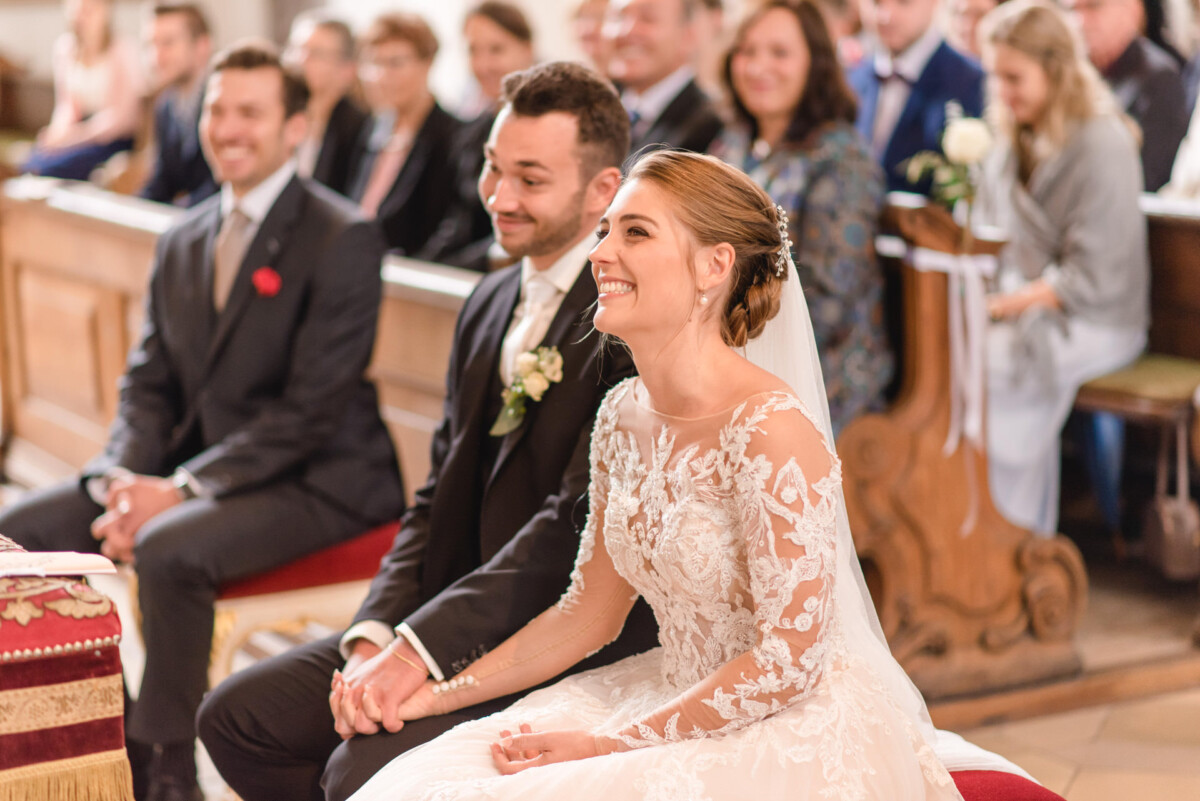 Sophia_Riccardo_Ammersee_00006 Ein Brautpaar sitzt in einer Kirche.