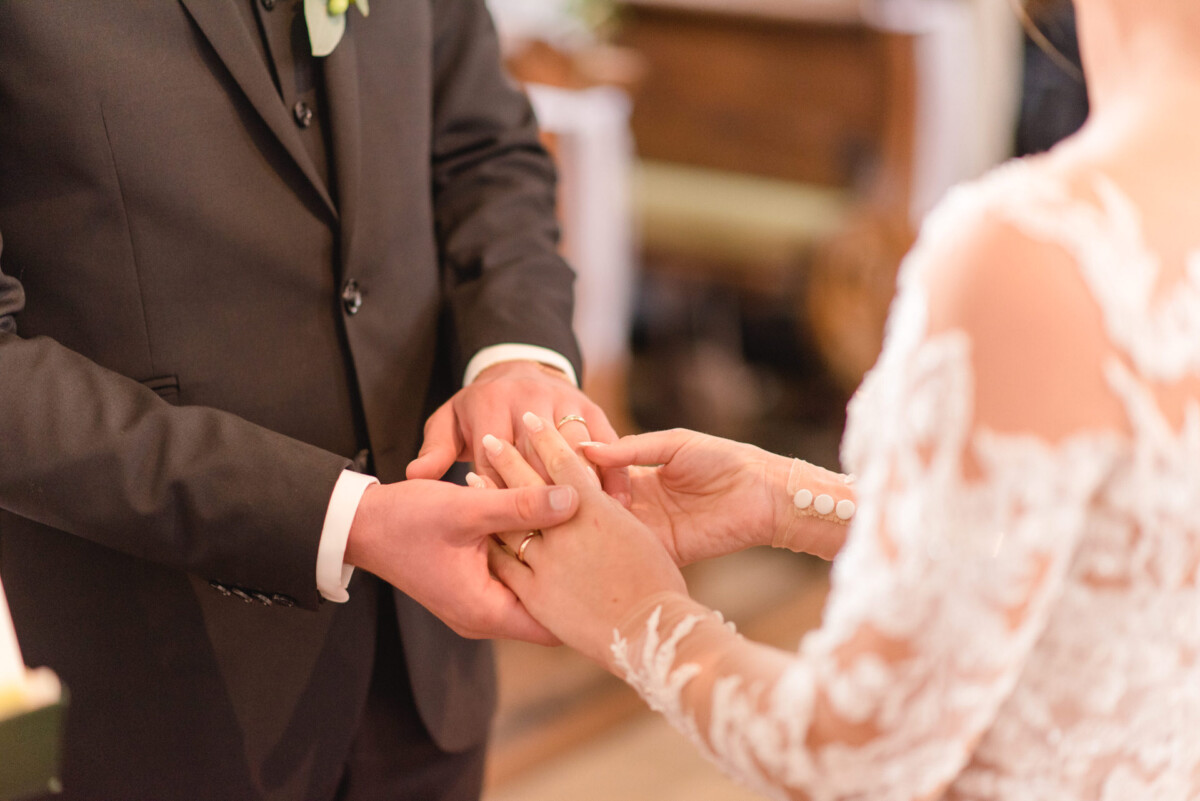 Sophia_Riccardo_Ammersee_00010 Ein Mann steckt einer Frau einen Ehering an den Finger.