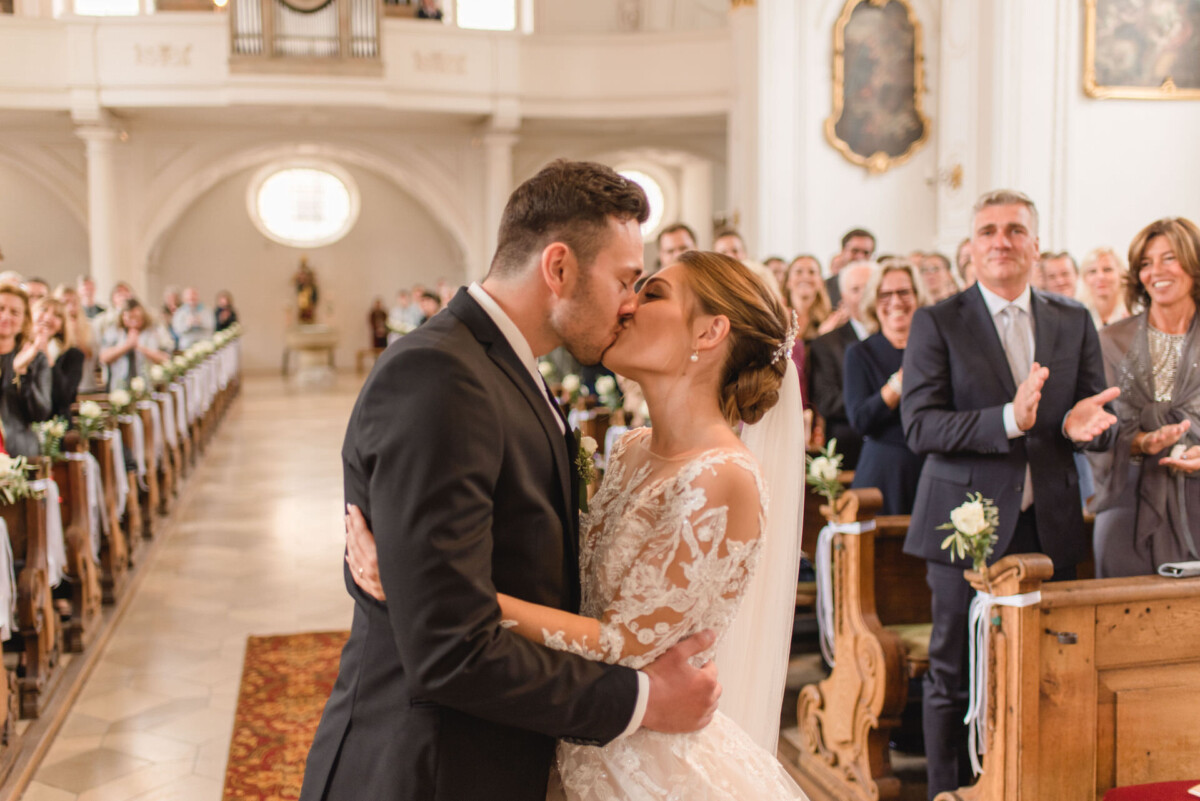 Sophia_Riccardo_Ammersee_00012 Ein Brautpaar küsst sich, als sie den Gang entlanggehen.