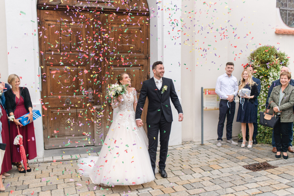 Sophia_Riccardo_Ammersee_00013 Ein Brautpaar geht durch eine Menschenmenge.