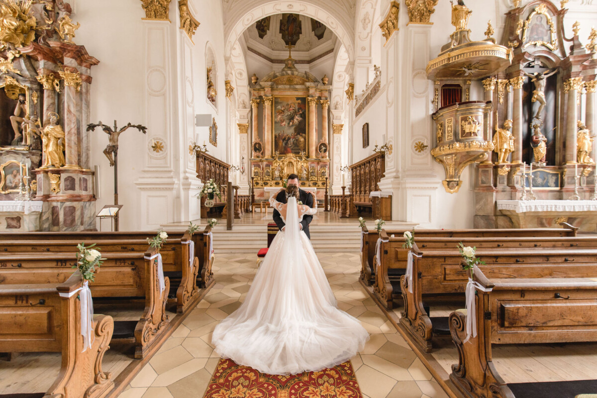 Sophia_Riccardo_Ammersee_00016 Ein Brautpaar steht in einer Kirche.