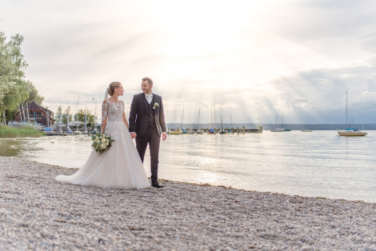 Sophia_Riccardo_Ammersee_00022 ein Brautpaar, das am Strand spazieren geht.