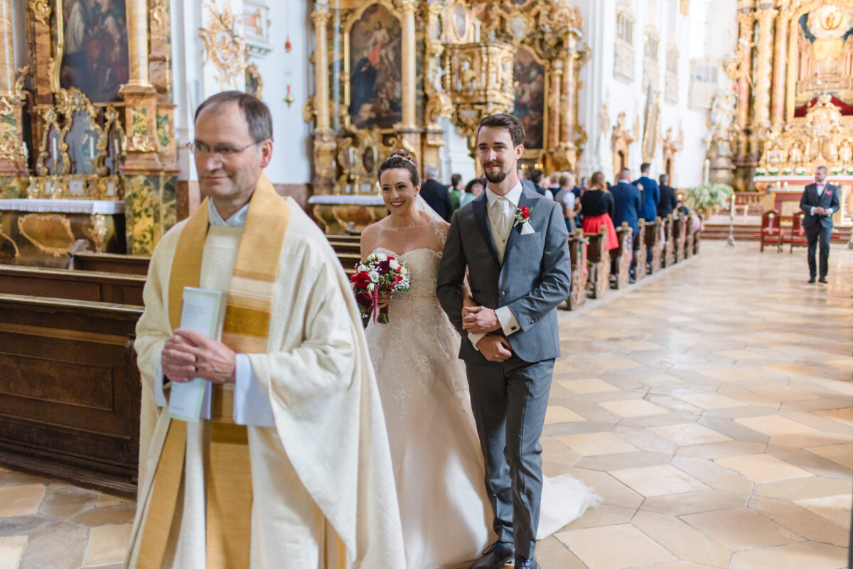 Stephi_Manu_Landsberg_am_Lech_00008 Ein Brautpaar, das den Gang einer Kirche hinuntergeht.