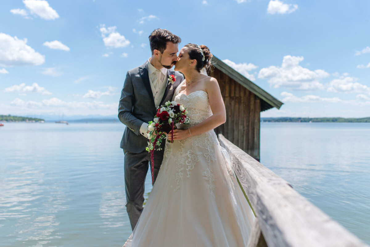Stephi_Manu_Landsberg_am_Lech_00009 Eine Braut und ein Bräutigam, die auf einem Dock am Wasser stehen.
