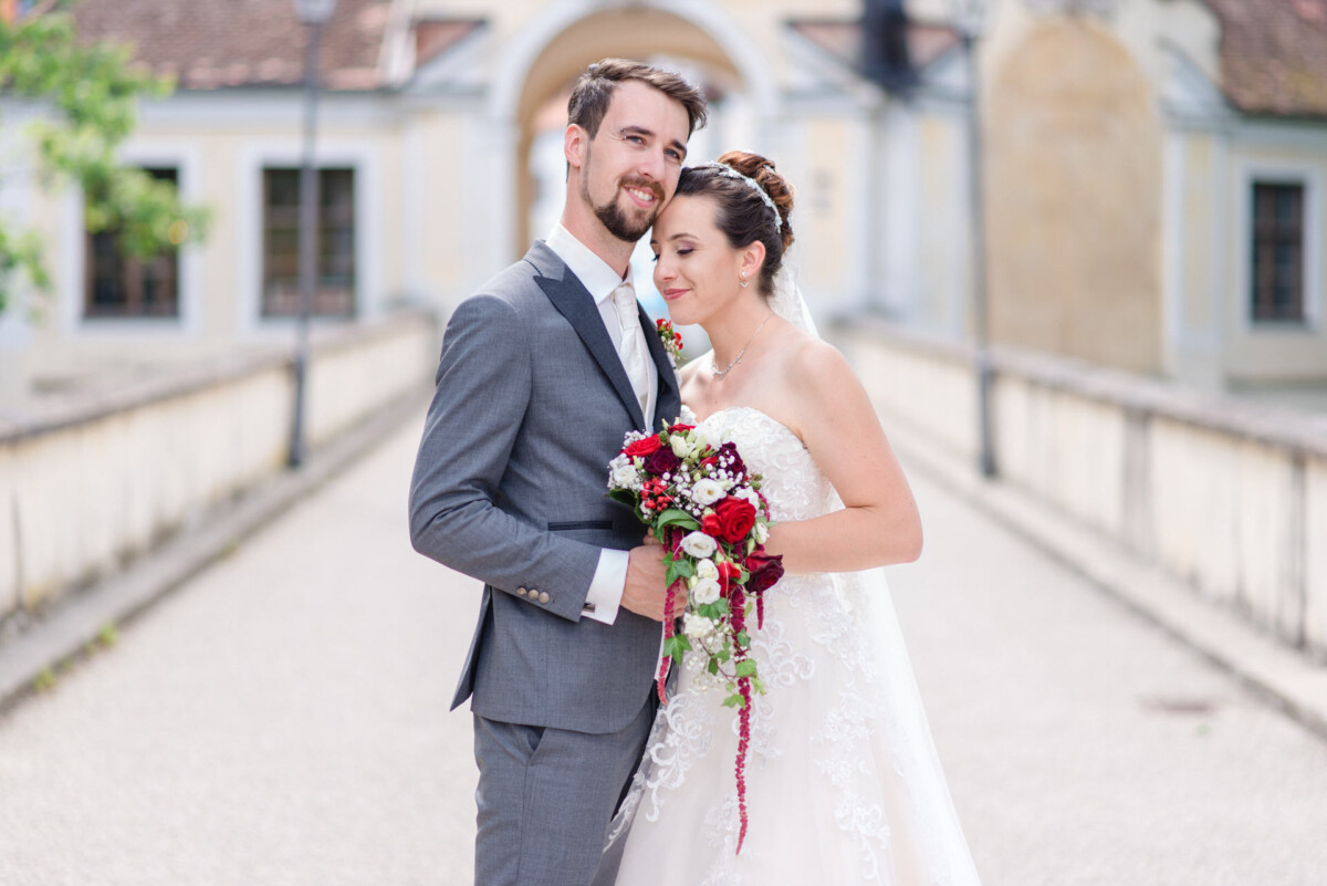 Stephi_Manu_Landsberg_am_Lech_00019 Eine Braut und ein Bräutigam posieren für ein Foto auf einer Brücke.