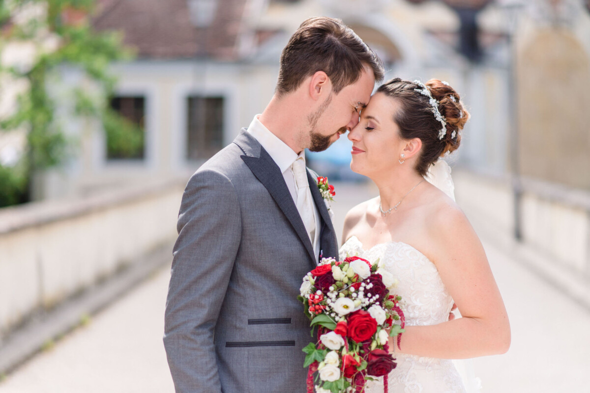 Stephi_Manu_Landsberg_am_Lech_00020 Eine Braut und ein Bräutigam posieren für ein Foto auf einer Brücke.