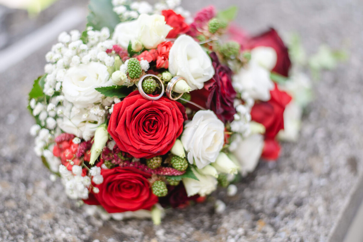 Stephi_Manu_Landsberg_am_Lech_00021 Ein Strauß roter und weißer Blumen, die auf einem Stein sitzen.