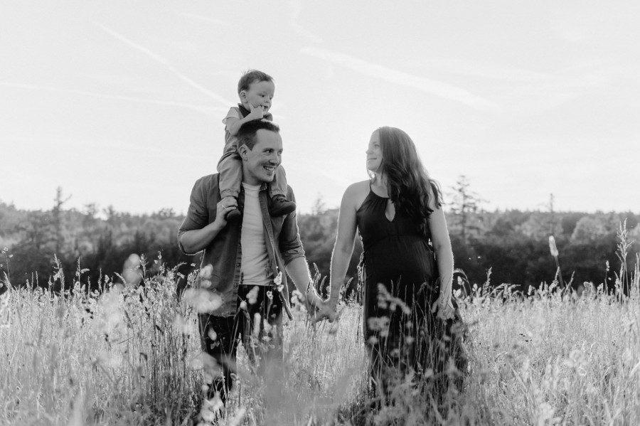 Natalie_Manuel_Bobingen_00006 ein Schwarz-Weiß-Foto einer Familie, die durch ein Feld geht.