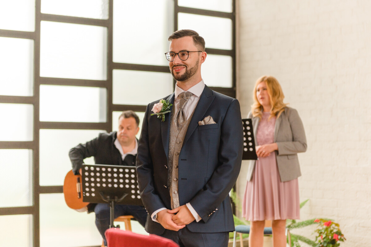 R_M_Bobingen_Langerringen_Hochzeit_00048_web Ein Mann in Anzug und Krawatte steht vor einer Gruppe von Menschen.