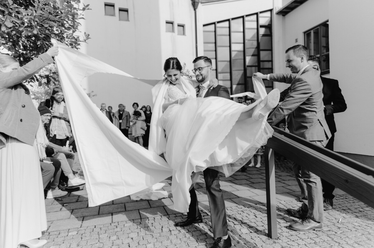 R_M_Bobingen_Langerringen_Hochzeit_00365_web ein Mann und eine Frau, die ein Hochzeitskleid halten.