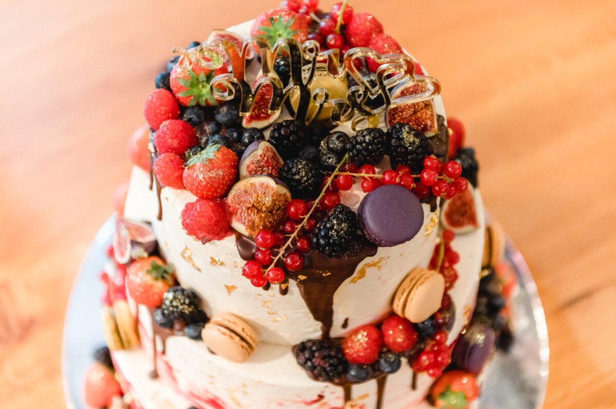 R_M_Bobingen_Langerringen_Hochzeit_00466_web ein weißer Kuchen mit Beeren und Nüssen.