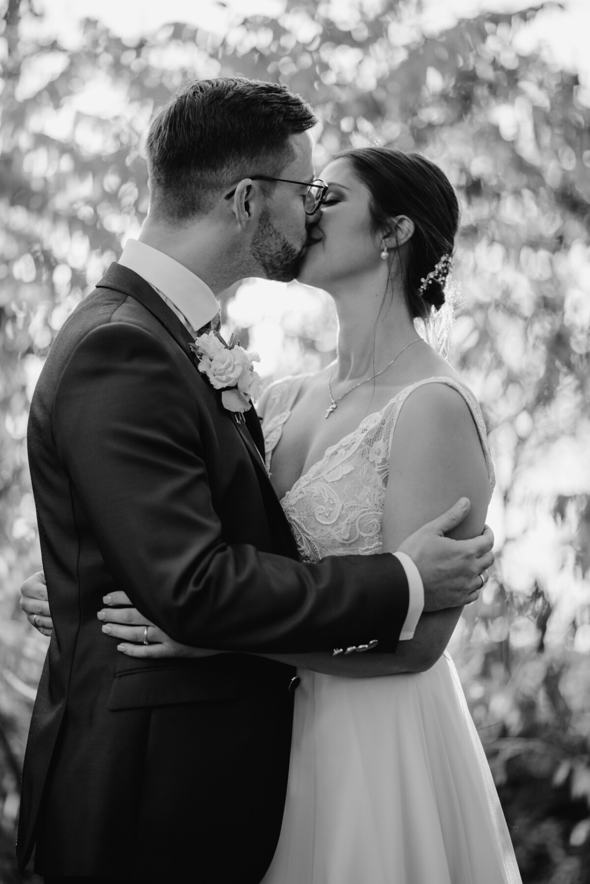 R_M_Bobingen_Langerringen_Hochzeit_00645_web ein Brautpaar, das sich vor Bäumen küsst.