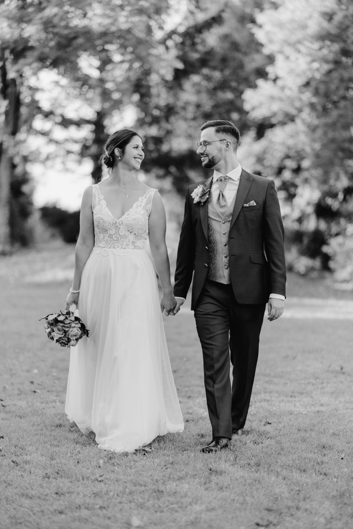 R_M_Bobingen_Langerringen_Hochzeit_00693_web ein Brautpaar, das auf einem Feld spazieren geht.