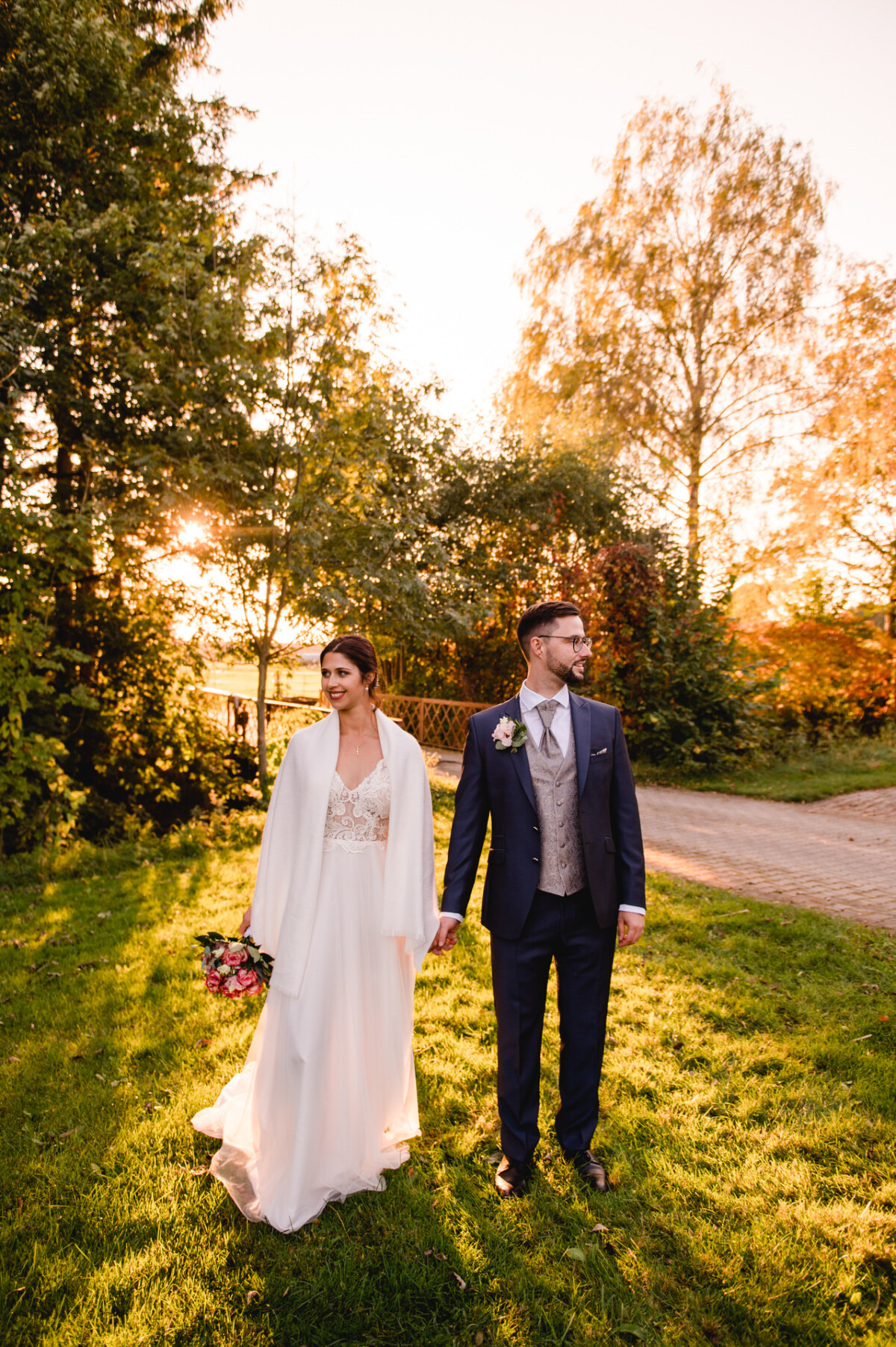 R_M_Bobingen_Langerringen_Hochzeit_00727_web ein Brautpaar, das im Gras spazieren geht.