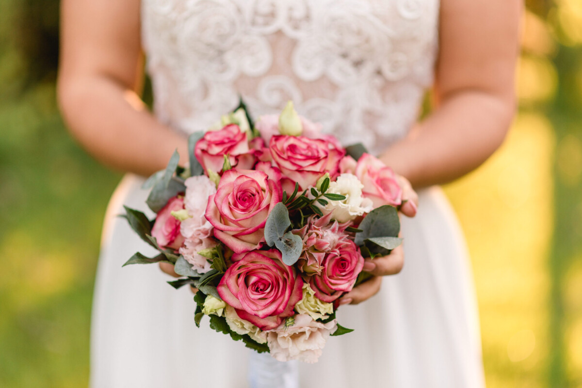 eine Braut, die einen Blumenstrauß aus rosa und weißen Blumen hält.