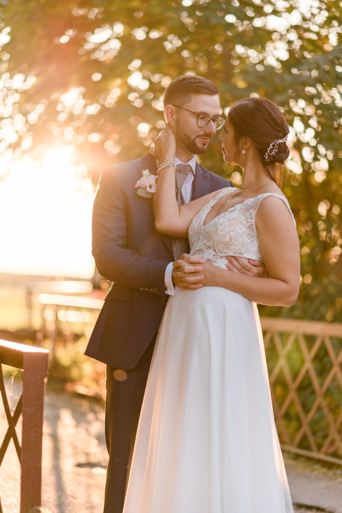 R_M_Bobingen_Langerringen_Hochzeit_00752_web Ein Brautpaar posiert für ein Foto vor der Sonne.