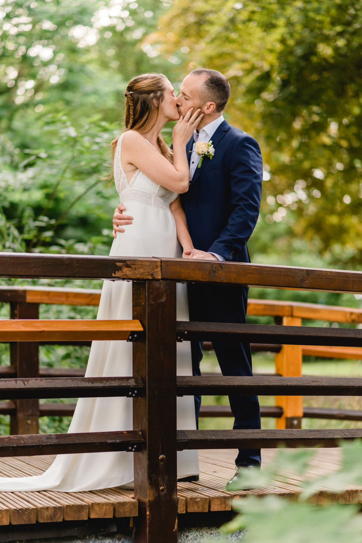 ein Brautpaar, das sich auf einer Brücke küsst.
