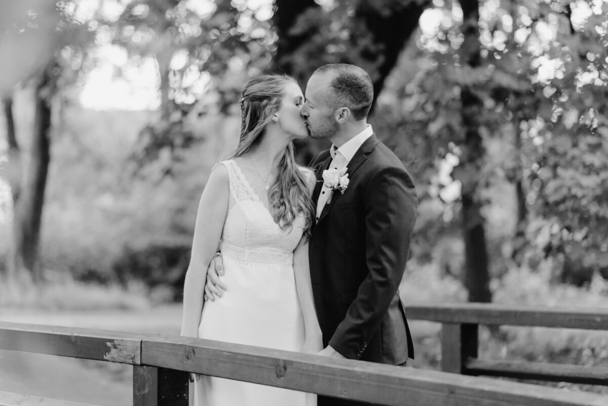 ein Brautpaar, das sich auf einer Brücke küsst.