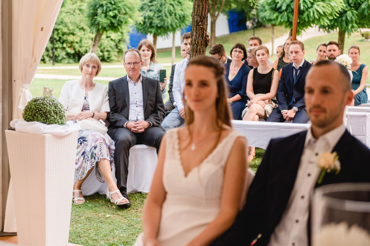 Ein Mann und eine Frau sitzen vor einer Gruppe von Menschen.