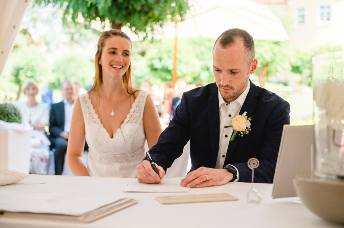 eine Braut und ein Bräutigam unterschreiben ein hochzeitsurkunde