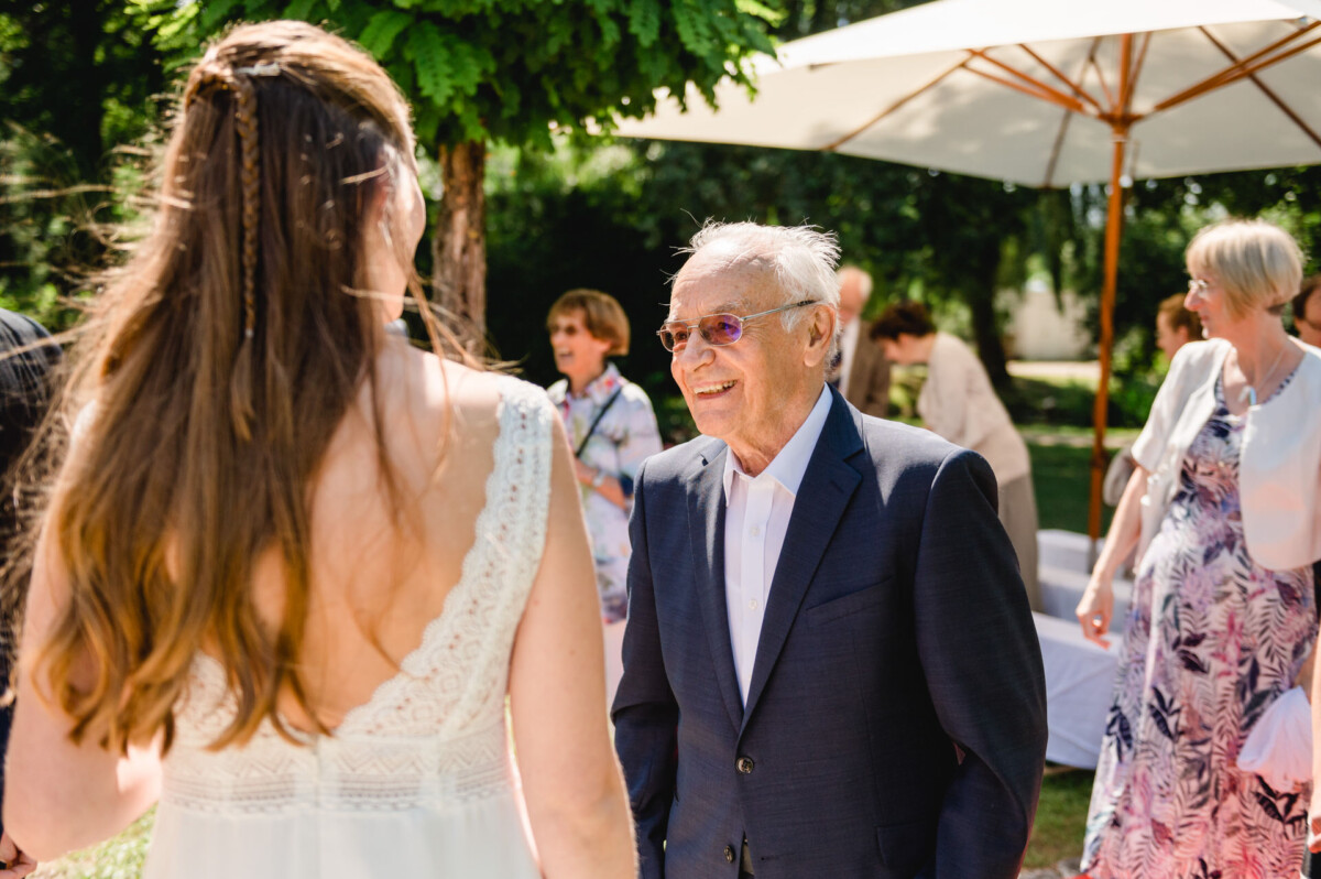 Ein Mann im Anzug spricht mit einer Braut im Kleid.