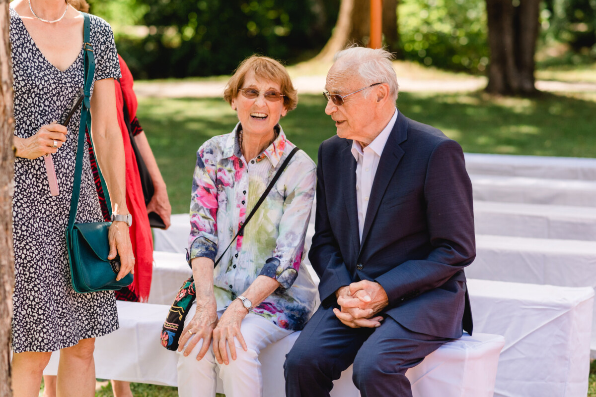 eine Gruppe von Menschen, die nebeneinander auf einer Bank sitzen.