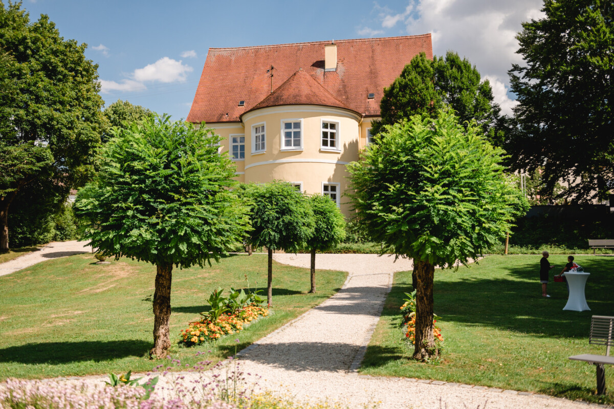ein Haus in einem Park mit Bäumen und einer Bank.