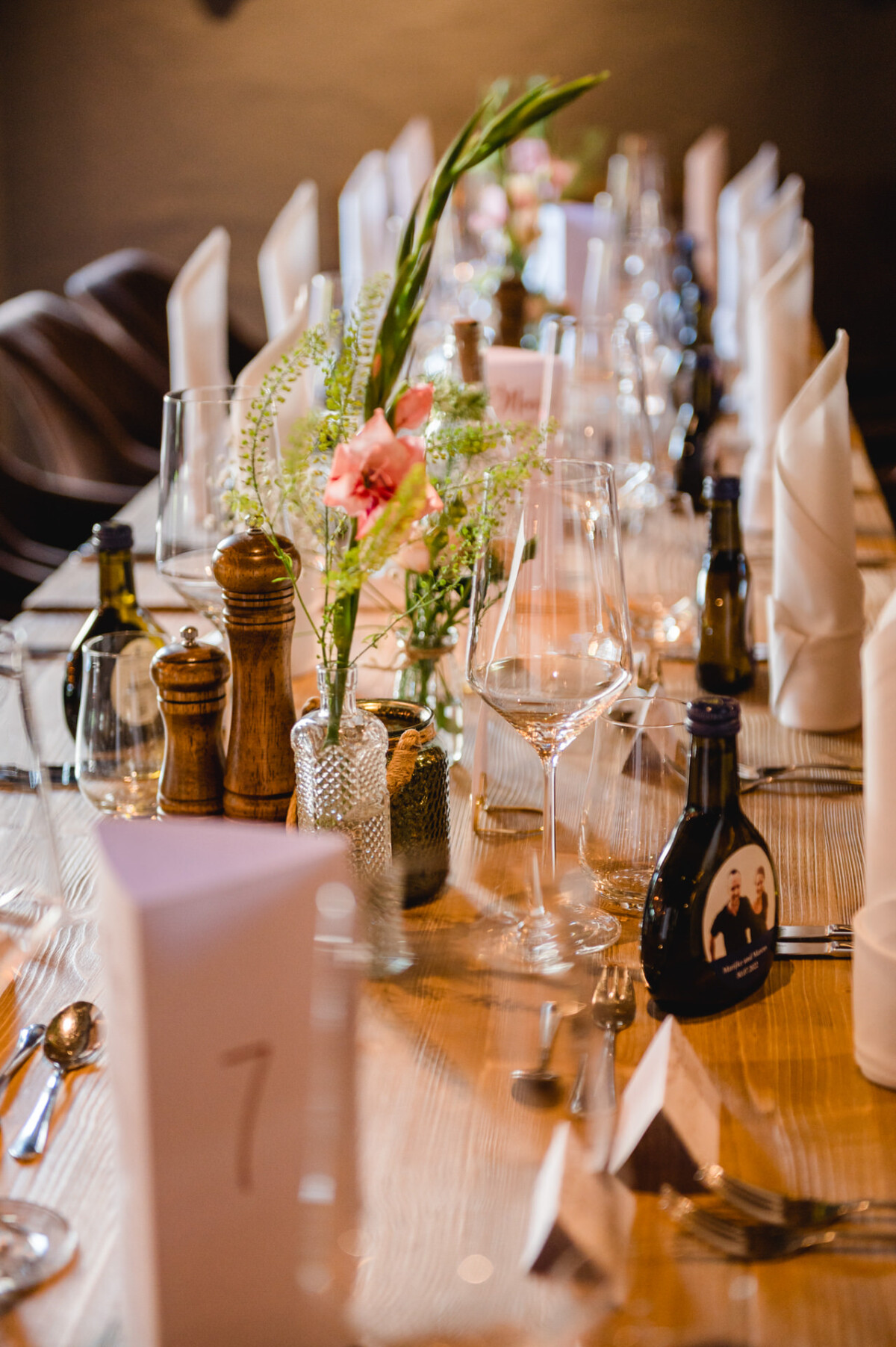 Ein langer Tisch ist mit Weingläsern und Besteck gedeckt.