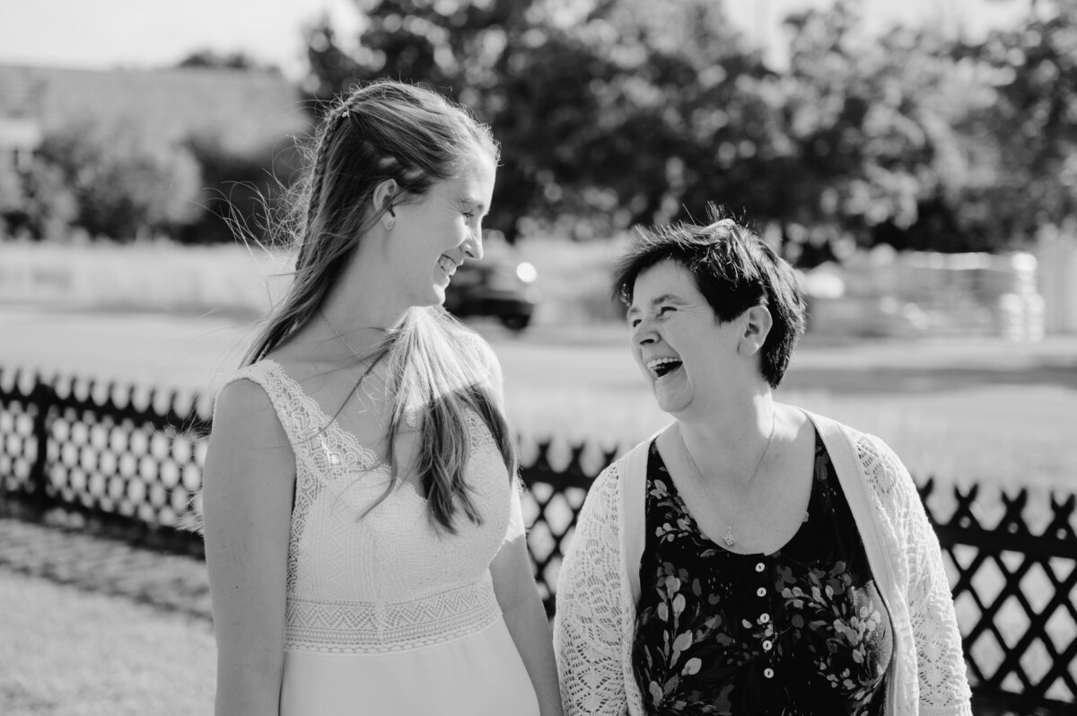 Zwei Frauen stehen nebeneinander in der Nähe eines Zauns.