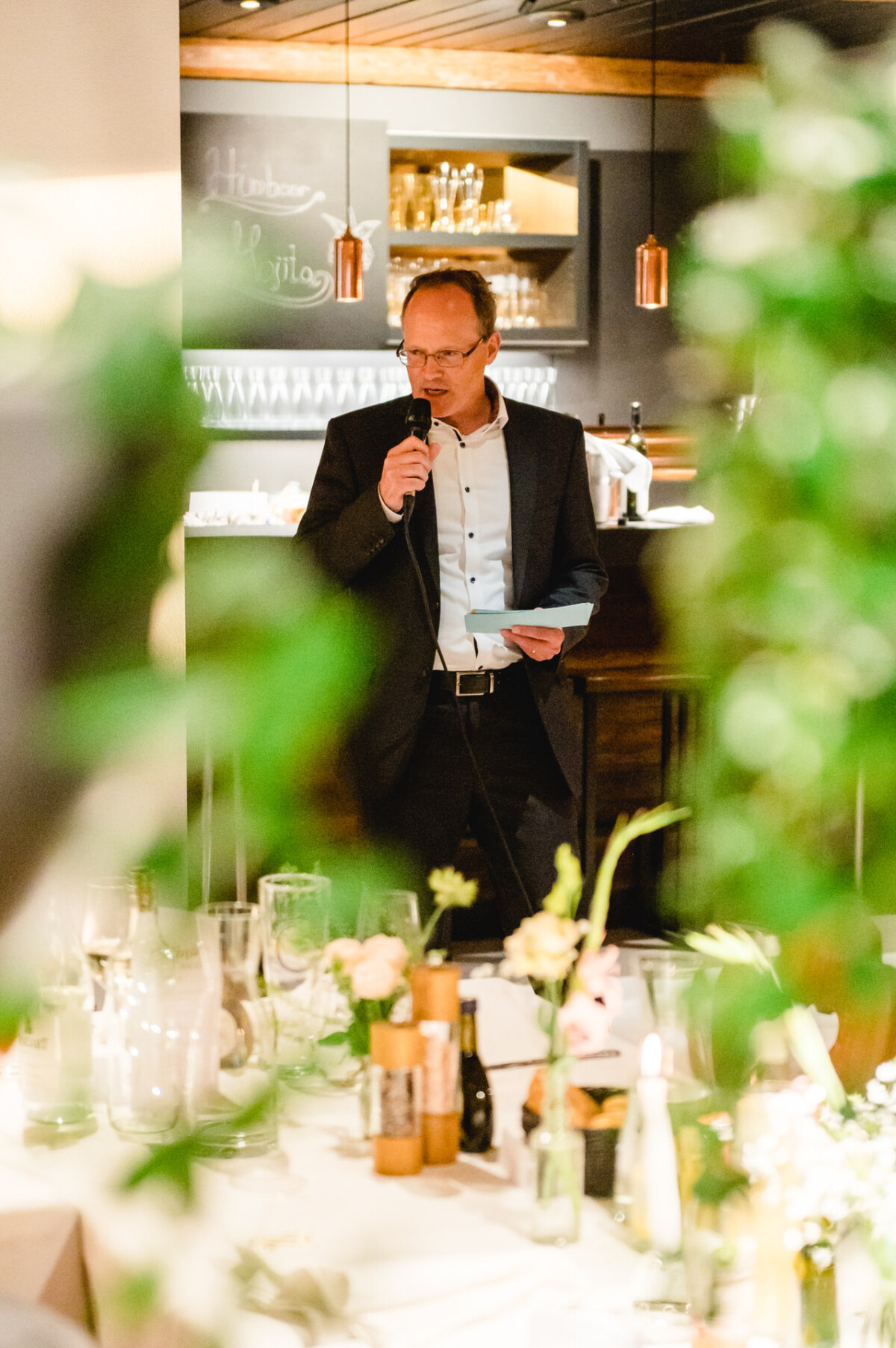 Ein Mann steht vor einem Tisch und hält ein Mikrofon.