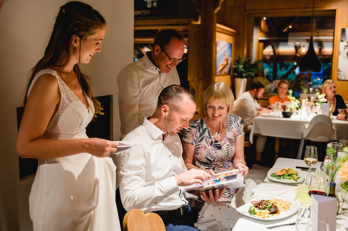 eine Gruppe von Menschen, die um einen Tisch mit Tellern mit Essen sitzen.