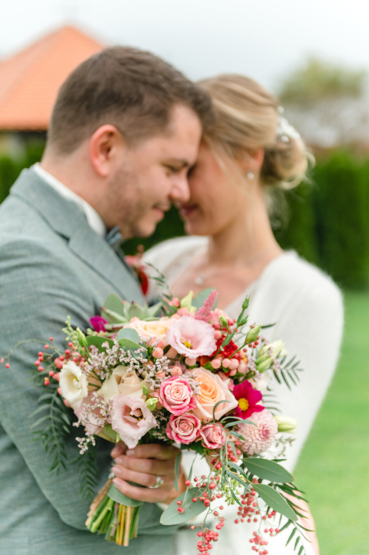 Ein Mann und eine Frau stehen nebeneinander und halten einen Blumenstrauß.